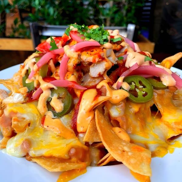 Steve's BBQ chicken nachos with melted cheese, pickled onions, jalapeños, and sauce.